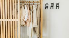 A wooden open closet with neutral cloths hanging