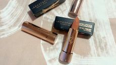 Anastasia Beverly Hills praline satin lipstck pictured twisted out of the tube, with the box behind it and tubes lying around