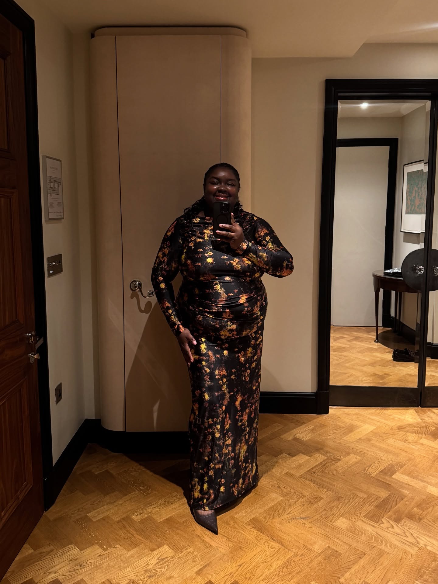 An image of @abimarvel wearing a long-sleeve floral maxi dress with brown mock croc pointed-toe heels.