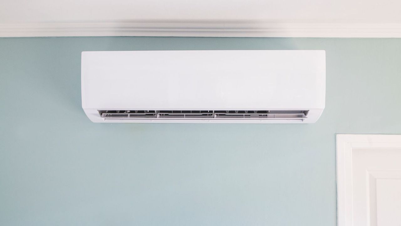 A wall mounted air conditioner on a blue wall