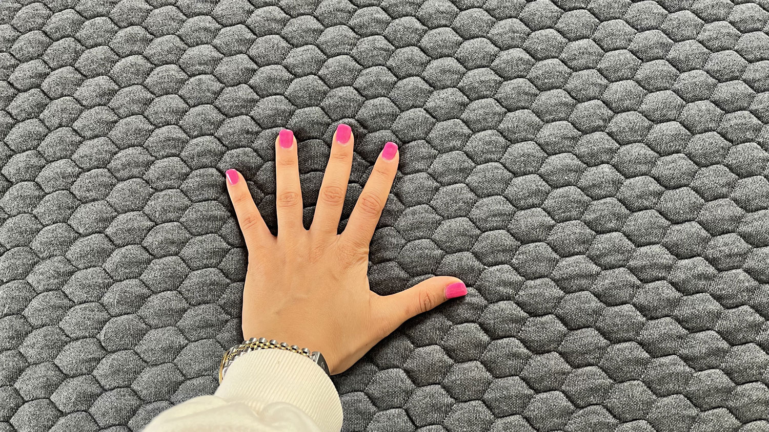 A hand pressing down on the Layla Hybrid Mattress