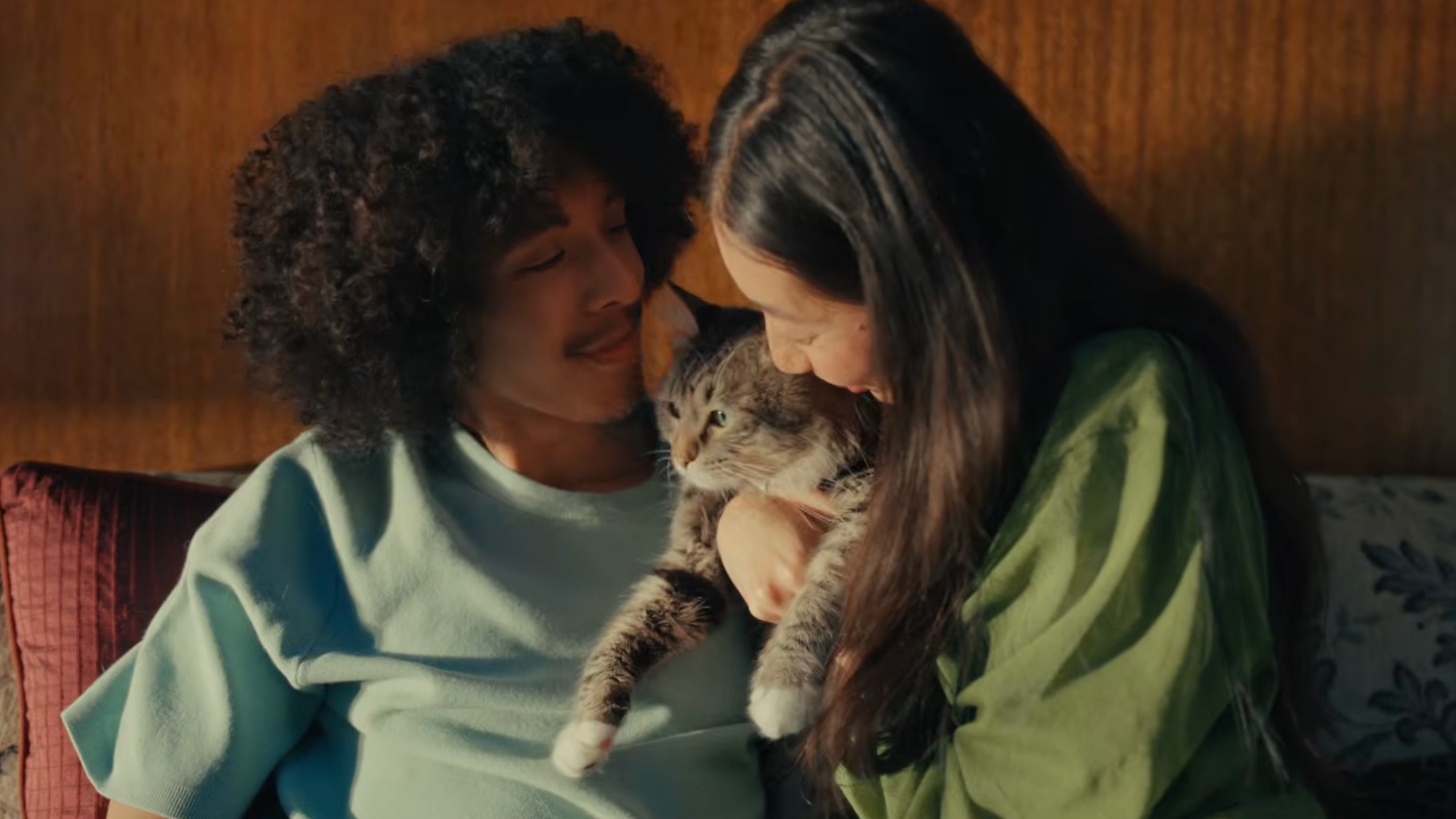 Man and woman on a sofa, cuddling a cat