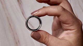 Oura Ring 4 held between a person's fingers