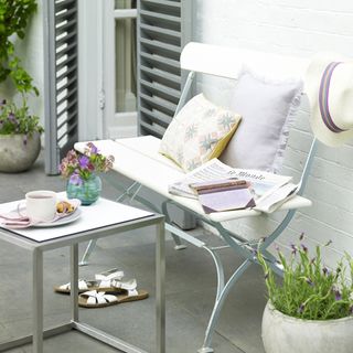 Patio with white wooden bench, white cushions and coffee table