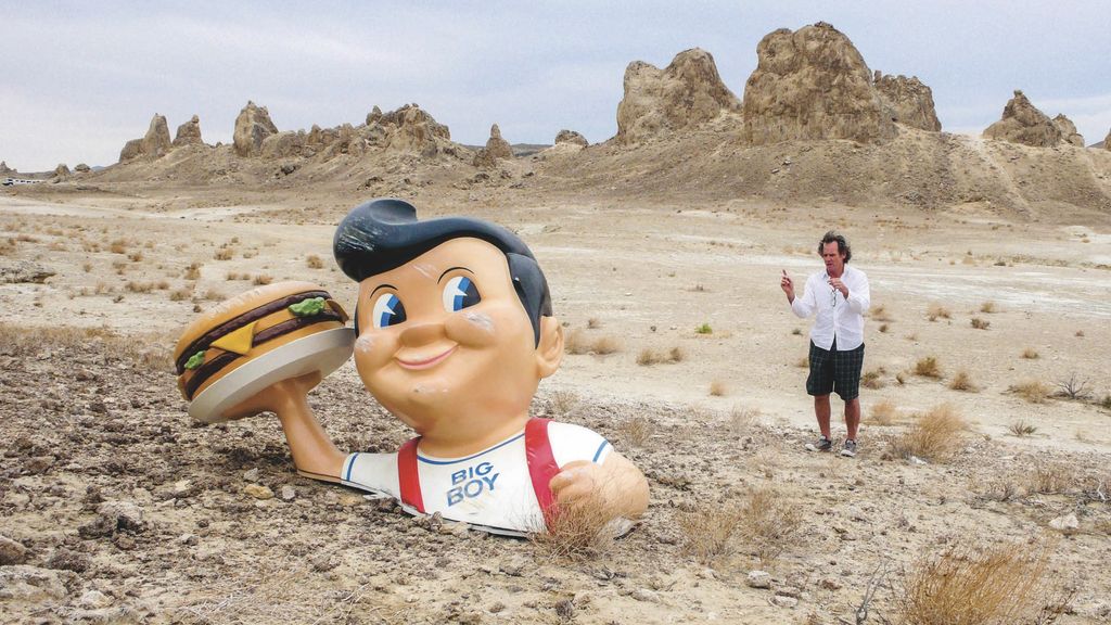 Figure holding a burger in the desert