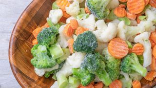 How do freezers work, and do they kill bacteria: a wooden bowl of frozen carrots, cauliflower and broccoli