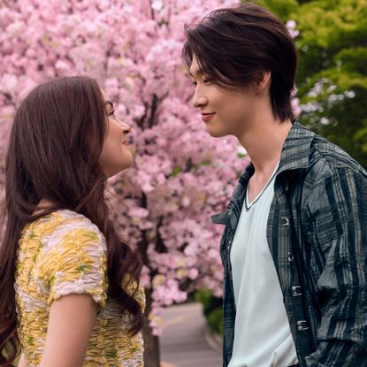 anna cathcart as kitty smiling and looking into tk's eyes outside standing in front of a cherry blossom in xo kitty season 3