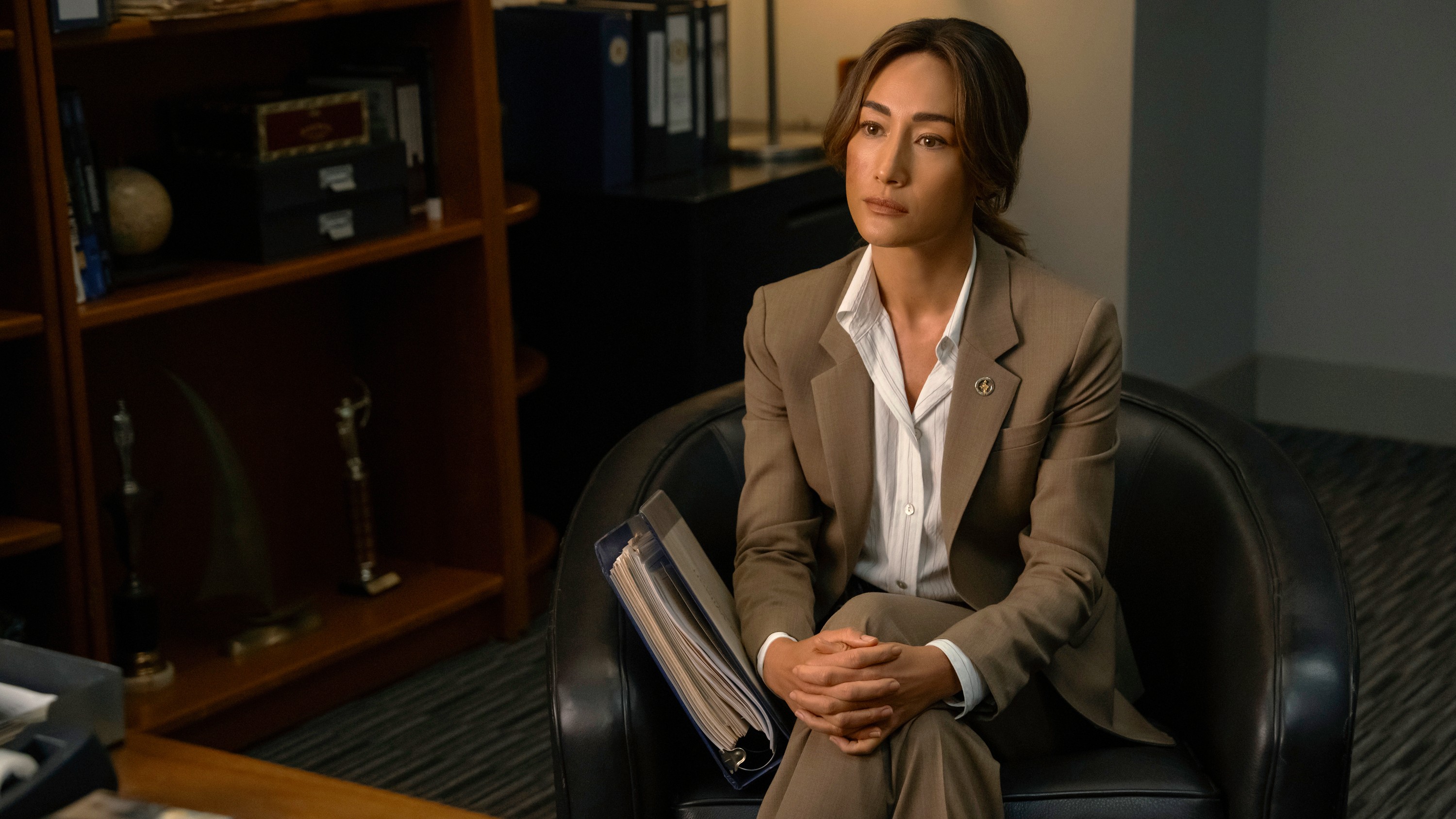 Renée Ballard (Maggie Q) sits cross-legged in an armchair in an office in a scene from Prime Video&#039;s &quot;Bosch&quot; spinoff, &quot;Ballard&quot;