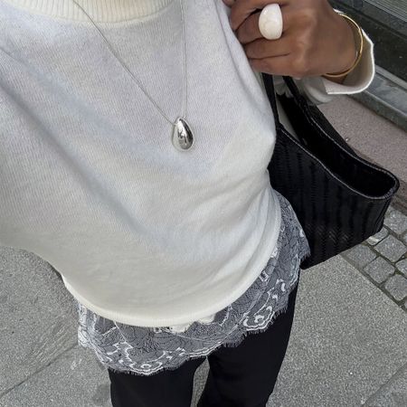 Woman in a sweater, black pants and lace-trim top