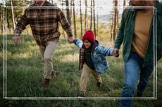 Little multiracial boy holding hands with father and grandfather when walking in forest