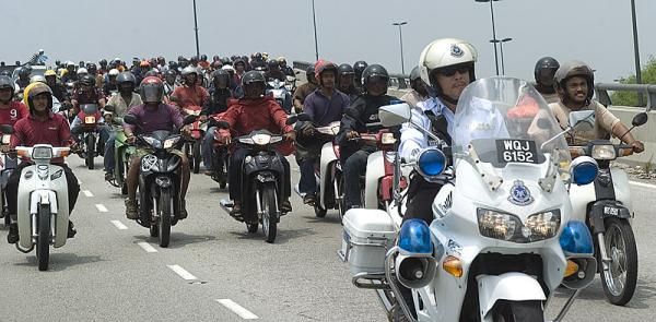 A Malaysian police solo makes sure the scooter army stay behind the race, and us, as the tour heads into Kuala Lumpur.