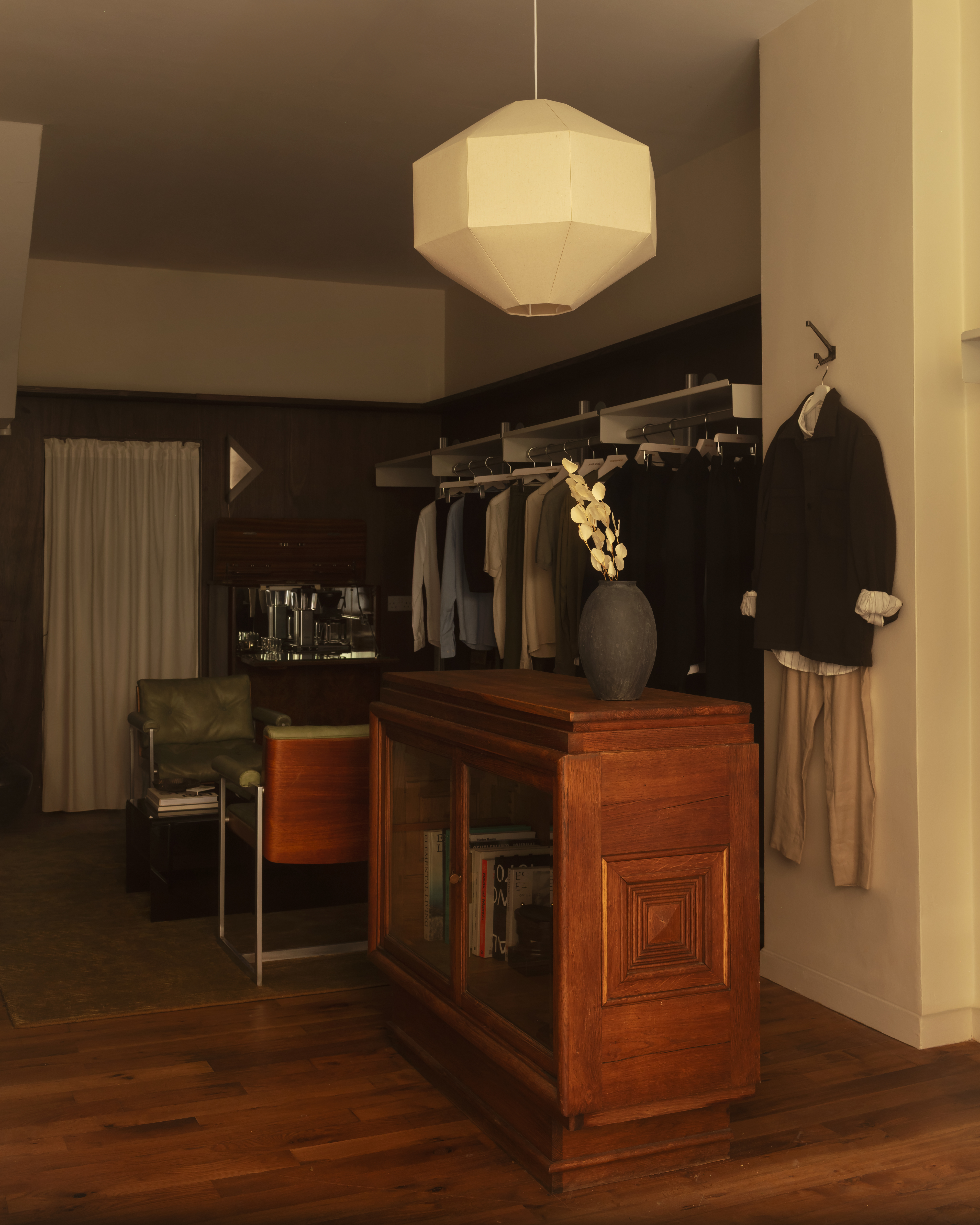 Different corners of a sleek menswear store clad in warm woods, beige drapery, and silver and mint green accents.