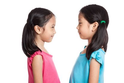 Asian twins girls smile look at each other isolated on white background.