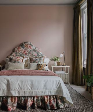 grandmillennial style bedroom with dusty pink walls and a statement floral headboard and bed skirt