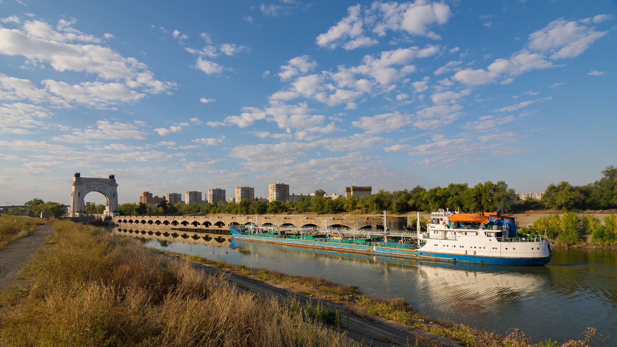 A view of a boat sailing down a waterway with grassy reeds on either side.