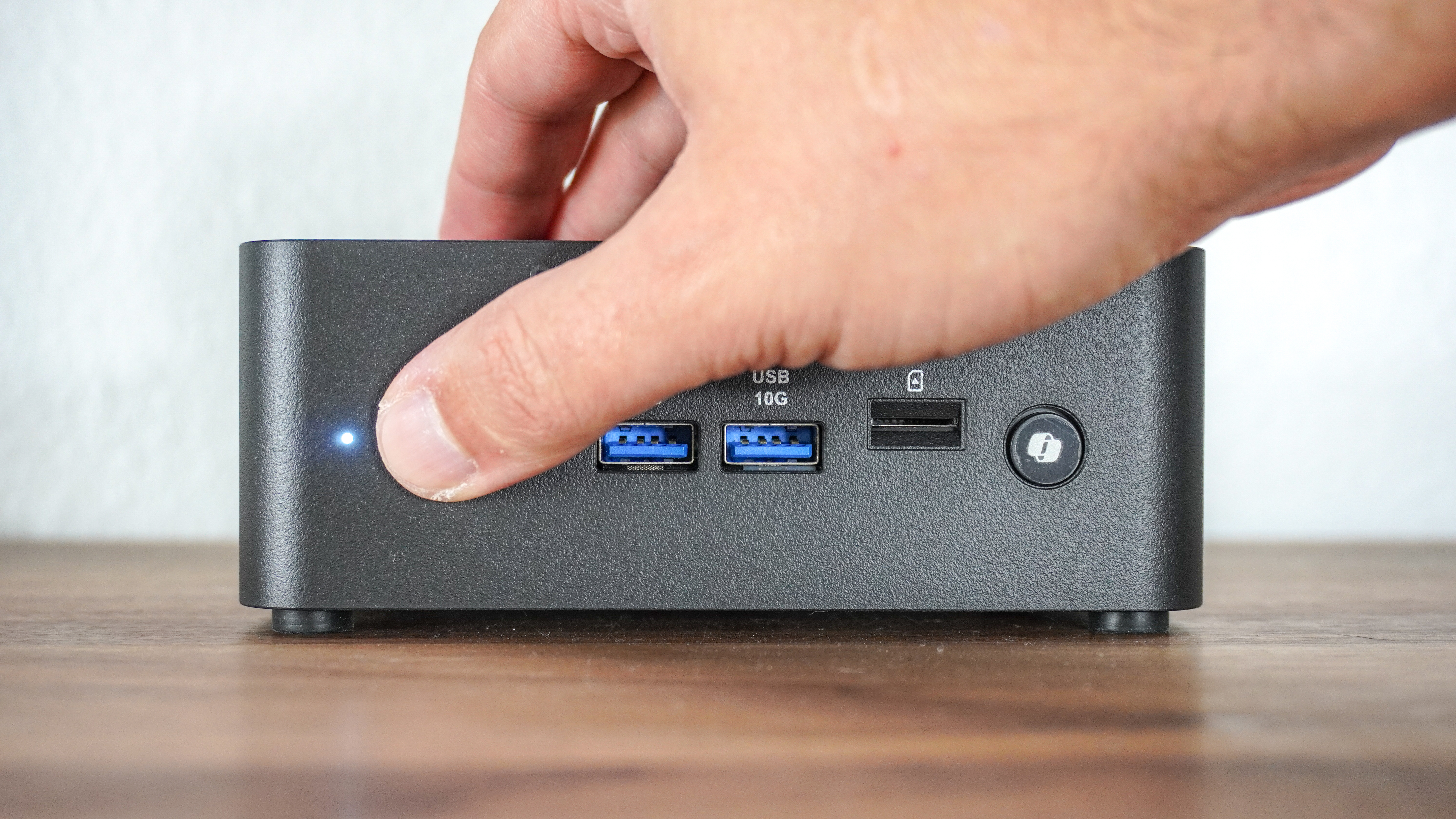 A person using the integrated fingerprint scanner in the power button of the MSI Cubi NUC AI+ 2MG mini PC