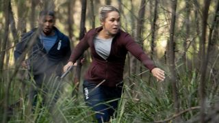 Evie and DeShawn running for their lives in a forest in NCIS: Sydney