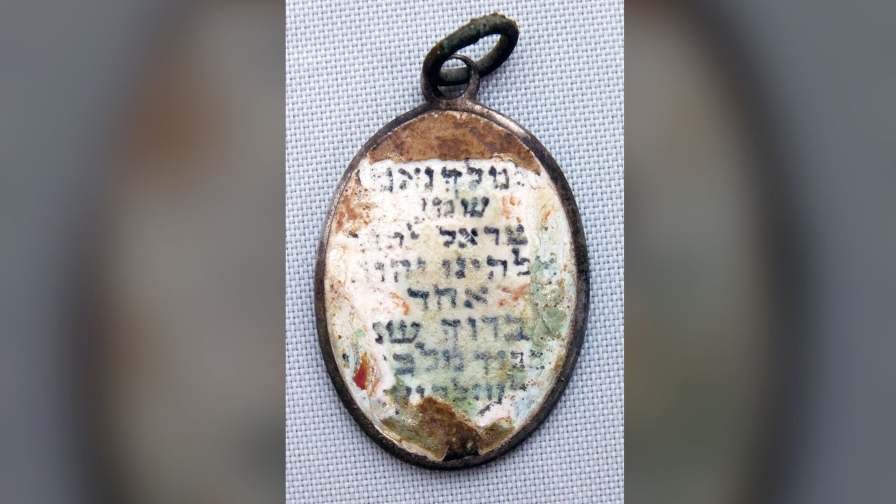 The pendant found by the mass grave at Sobibor. Only the side with the Shema survived.