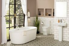 downstairs bathroom with a freestanding modern bath, white metro tiles and soft pink walls