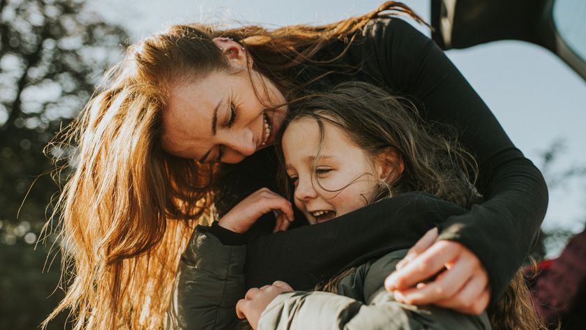 A woman is shown embracing her child and looking down at her. 