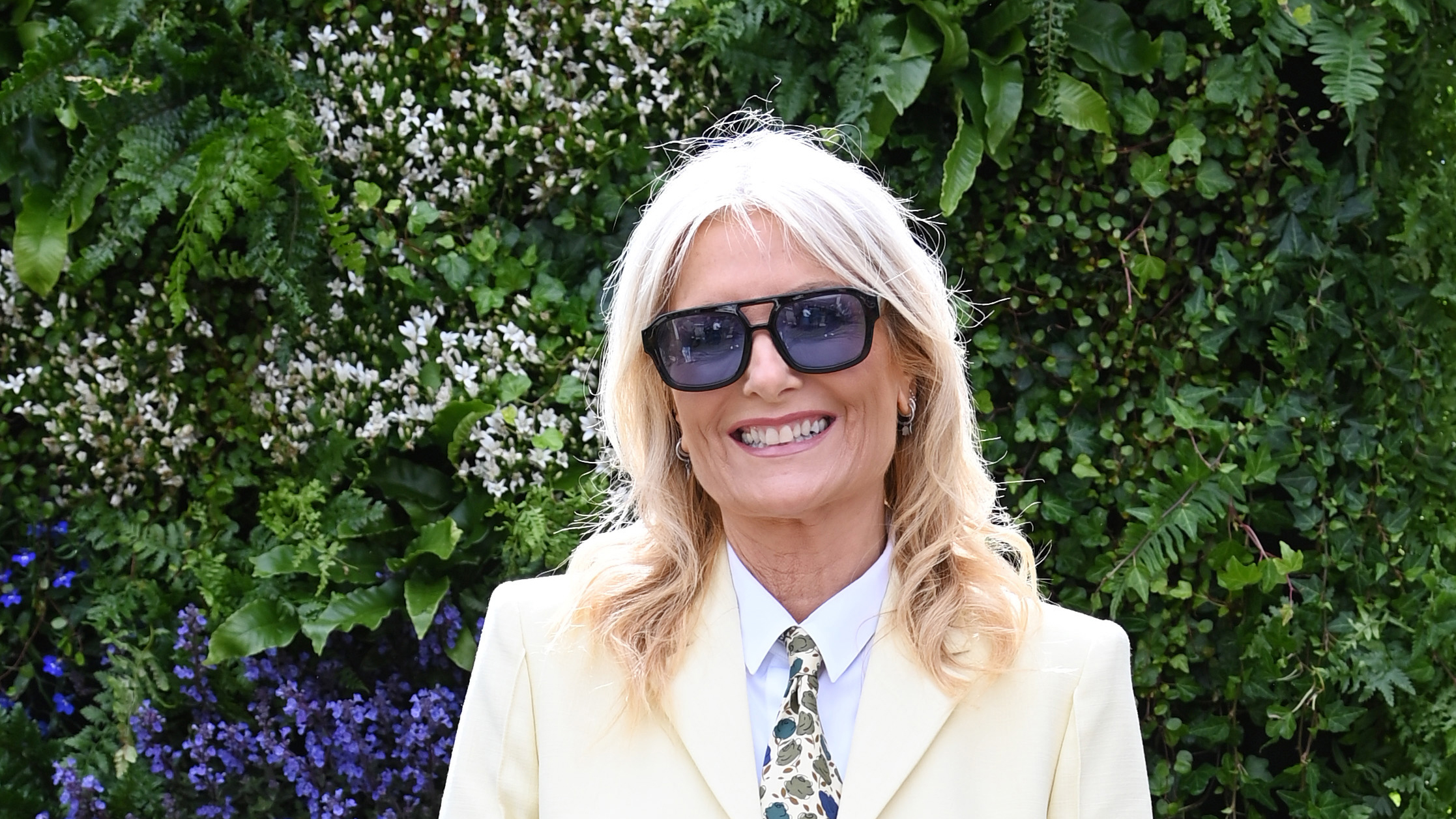Gaby Roslin wearing a cream suit and purple sunglasses