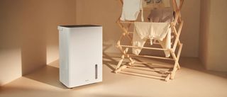 A white Duux dehumidifier next to a clothes drying rack