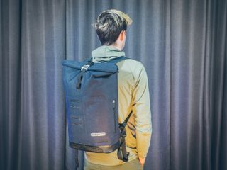 Will Jones, wearing one of the best backpacks for cycling, stands in front of a wall