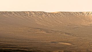 a vast rusted orange landscape sloping upward to a faraway crater edge.