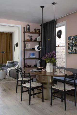 dining room with pink walls, wood oval table and black shelves
