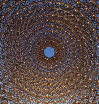 Interior view from below of the aluminium mesh ’beehive’ structure at the UK Pavilion - the structure has a hole at the top and it is illuminated by rings of small lights