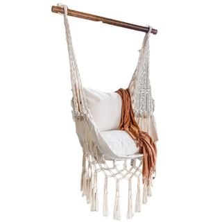 A macrame hanging chair with an orange blanket