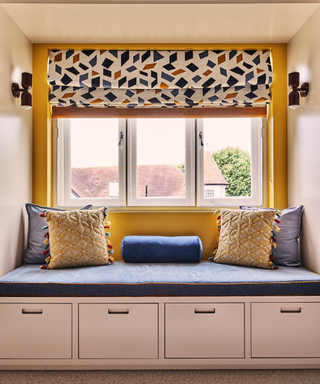 a yellow painted bay window with a banquette seating below