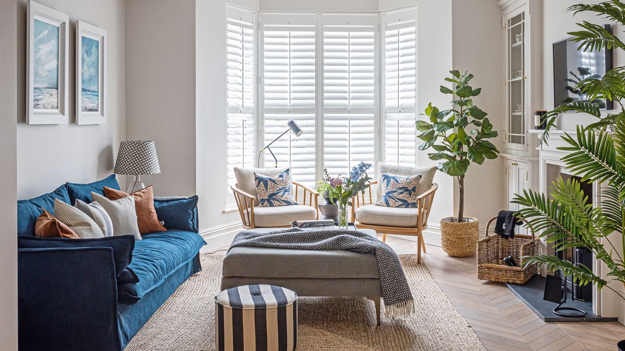 A blue sofa and wooden chairs in the bay window of a modern family home