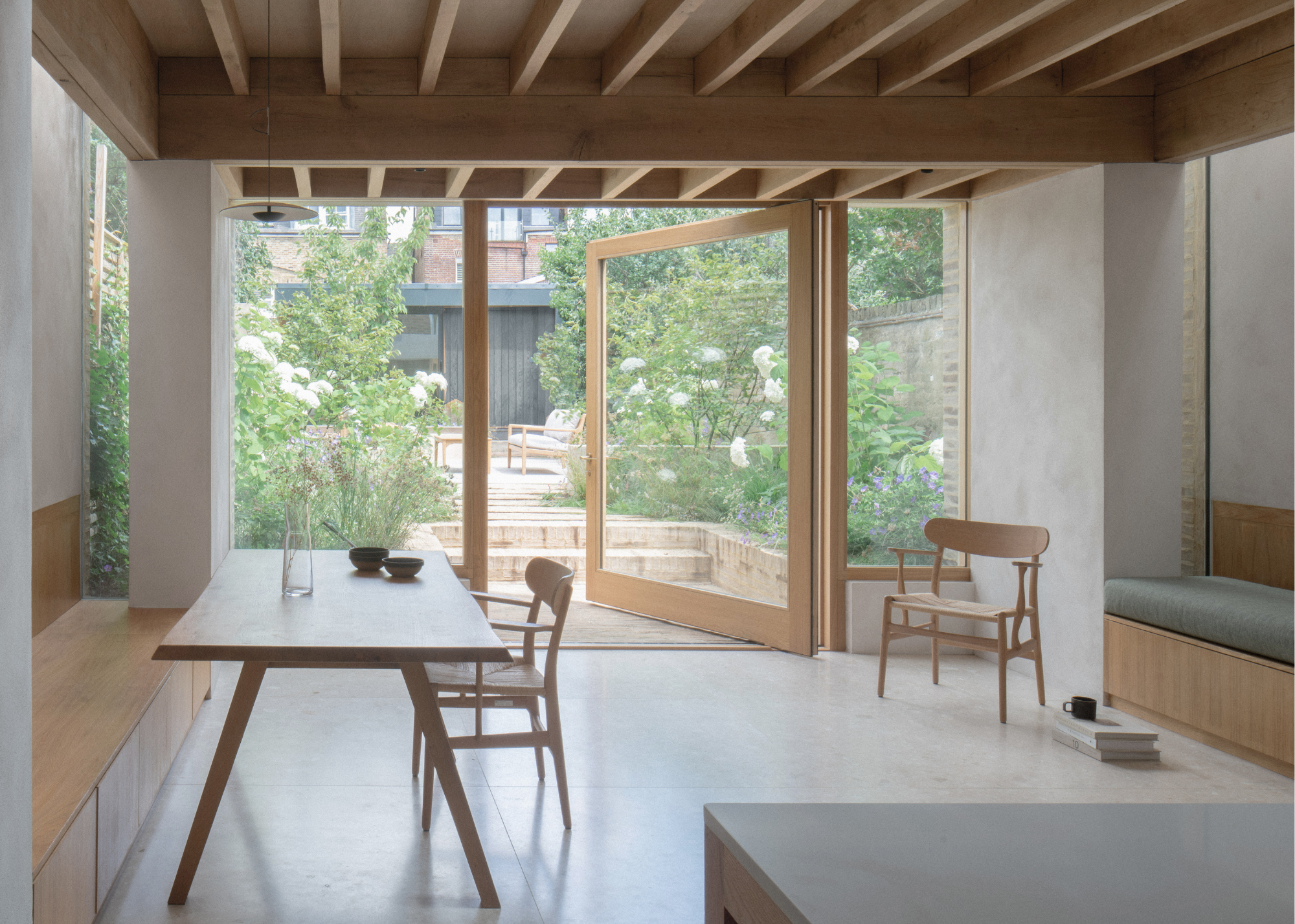 beautiful glass and wood kitchen dining area with panelled wood ceiling and open glass doors