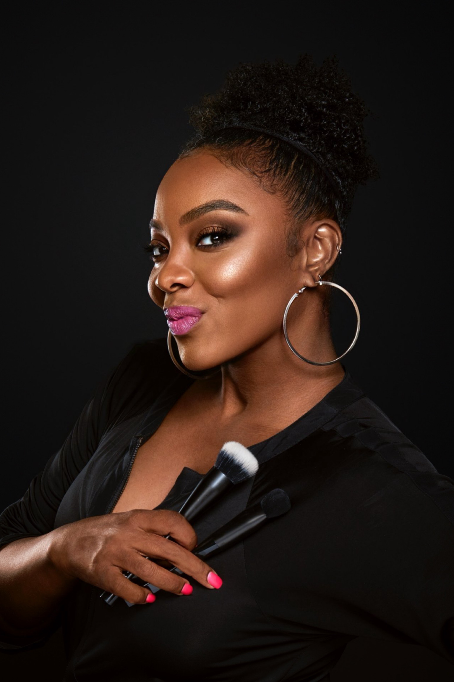 a black woman with pink nails and dark hair in a black jacket