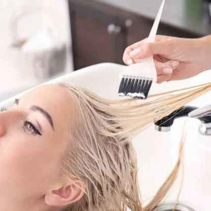 A woman getting her hair bleached in a salon.