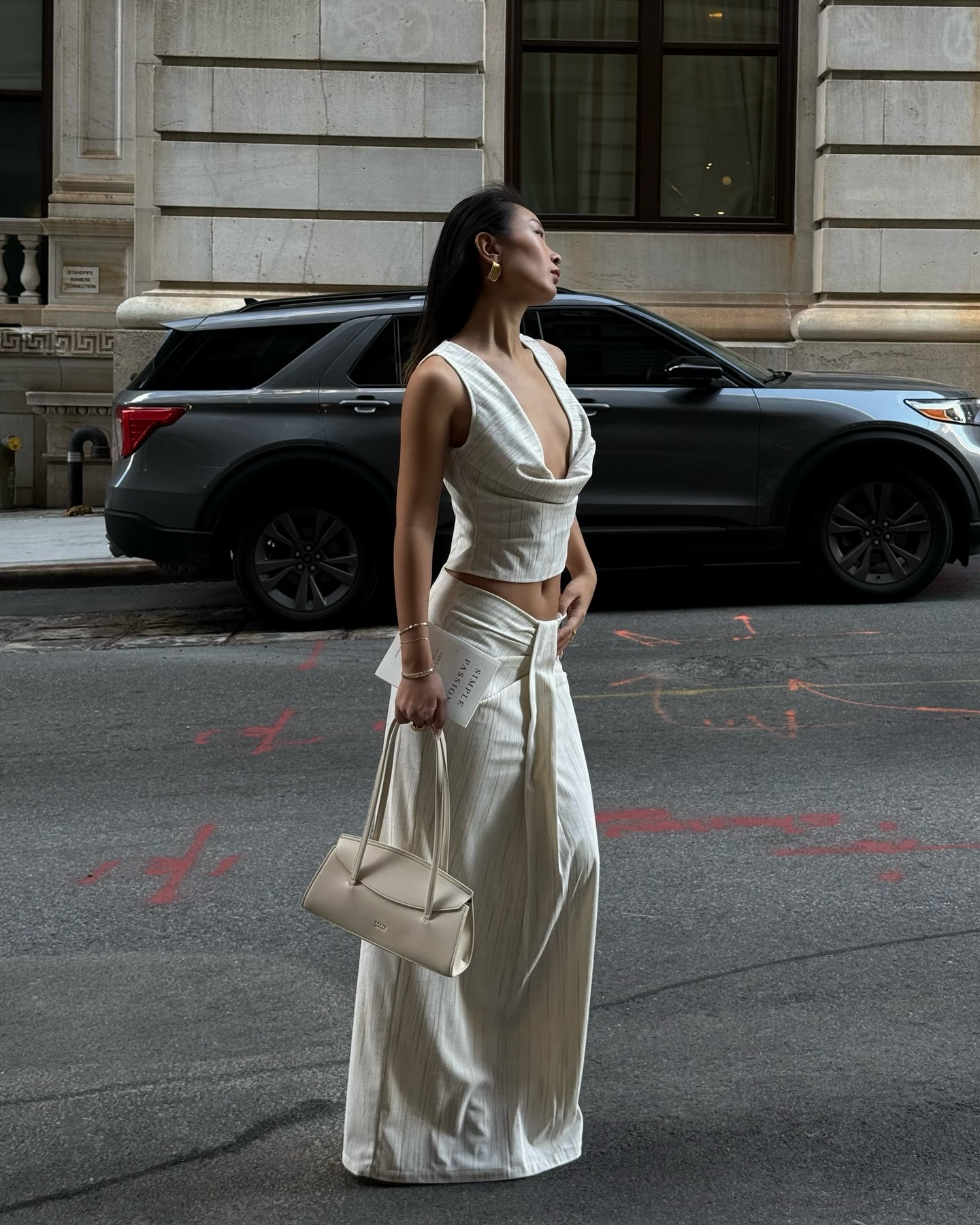 Caroline wears a white top, white maxi skirt and carries cream bag