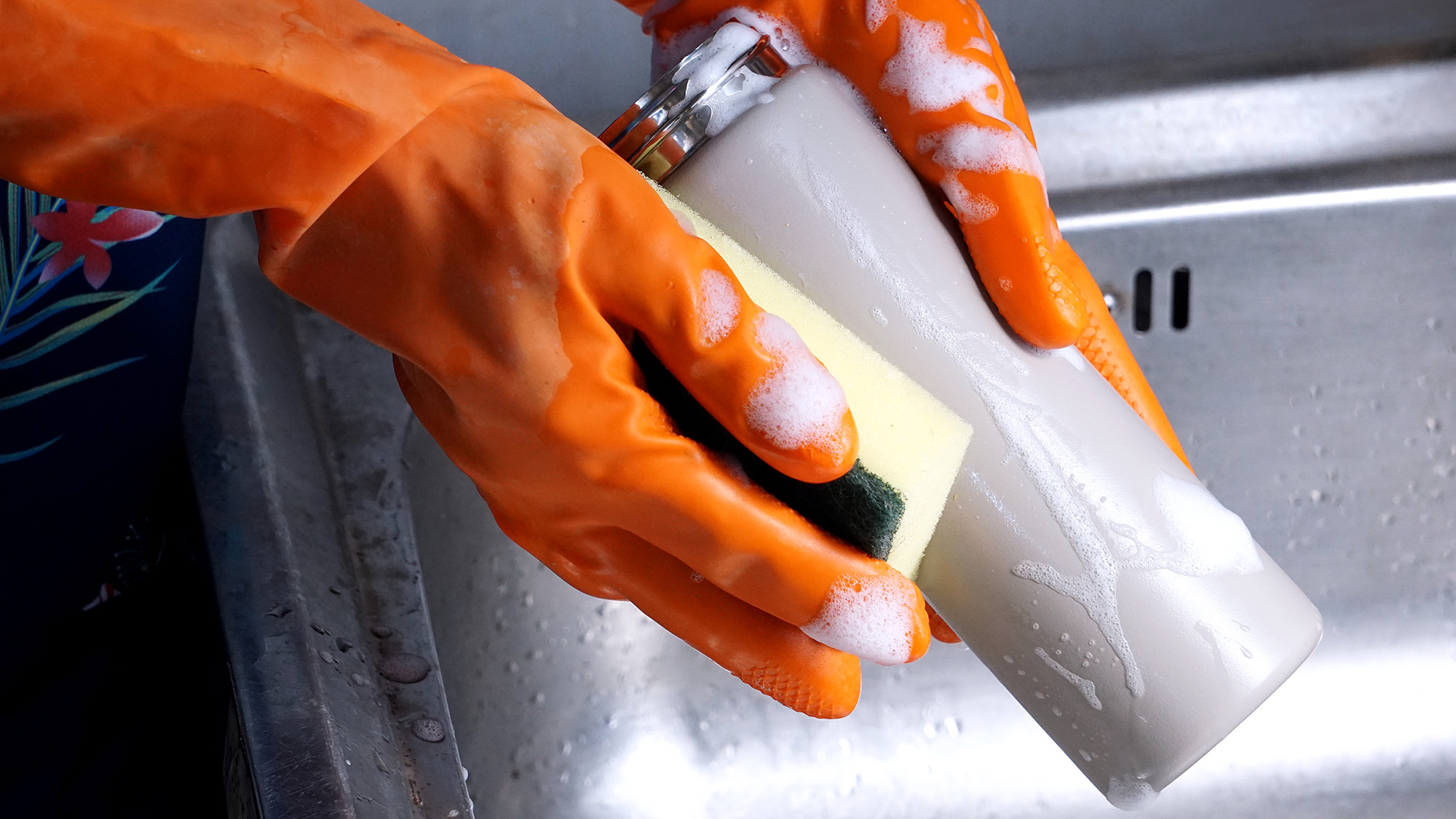Person wearing gloves and cleaning a water bottle