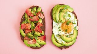 Slices of wholegrain toast with fried egg, avocado, and chopped tomatoes