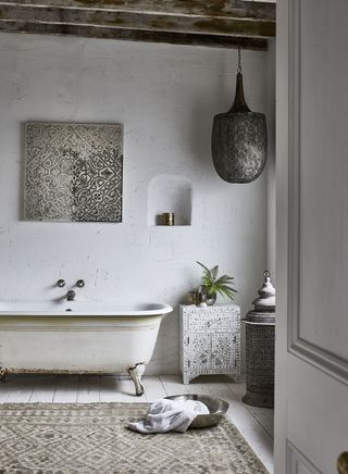 rustic bathroom items, such as a cabinet and freestanding bath in a white, Moroccan-style bathroom