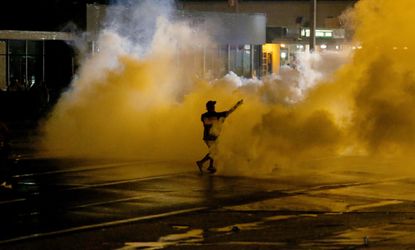 A man throws a gas cannister back at police in Ferguson, Mo.