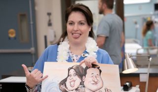 Alex holding caricature of her and hubby in St. Denis Medical Season 2