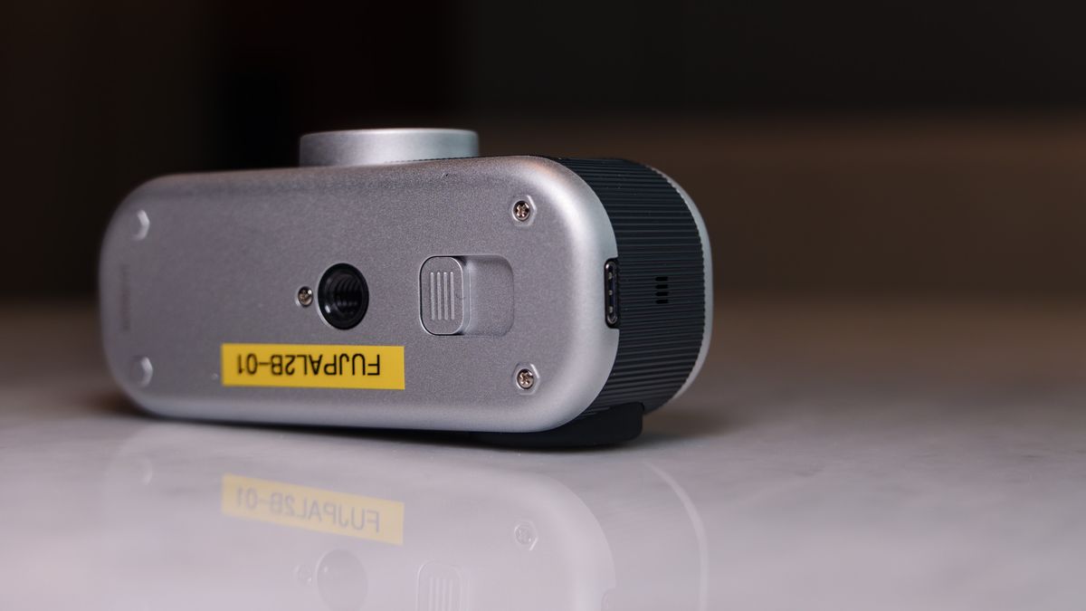 Fujifilm Instax Pal 2 digital camera on a marbled white surface, close up of the underside USB-C