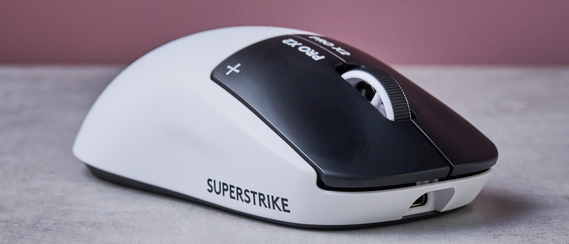 Three-quarter view of Logitech G Pro X2 Superstrike on white desk with pink wall in background