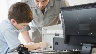 Man and boy plugging a printer into a computer.