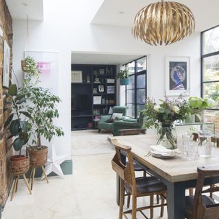 dining room with chairs, house plants, laminate flooring white walls with a skylight and gold pendant