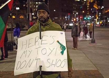 A man holds a sign referring to the police shooting of Tamir Rice, a 12-year-old boy who had a toy gun.