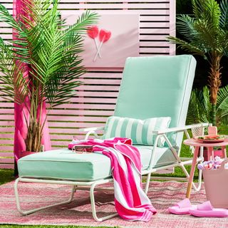 lounger on outdoor rug with pink fence and outdoor furniture