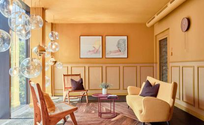 Lindley Lindenberg lounge with yellow wall panels, yellow sofa and hanging glass lamps