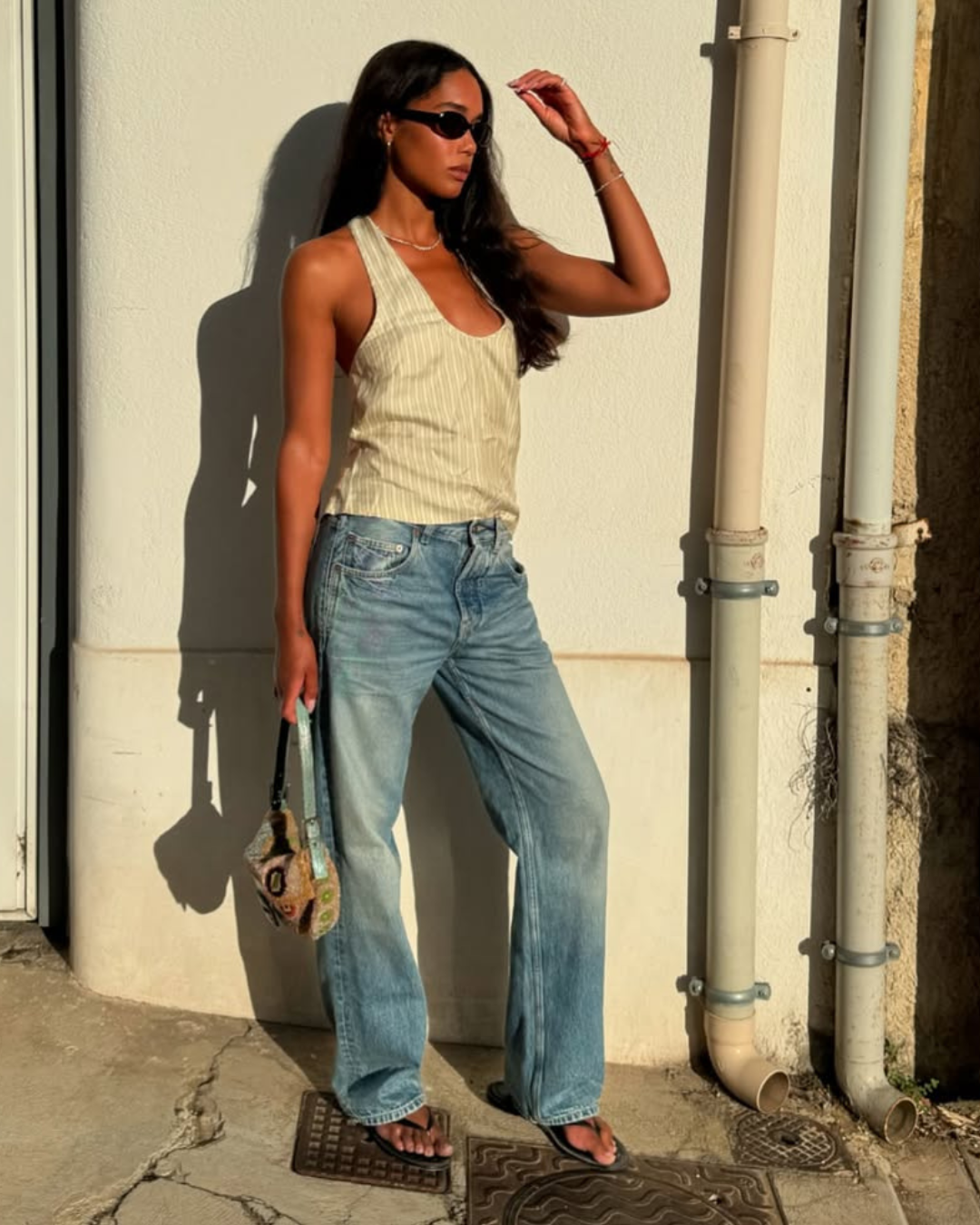 @lauraharrier çizgili askılı bir üst, düz paça kot pantolon ve parmak arası terlik giyiyor